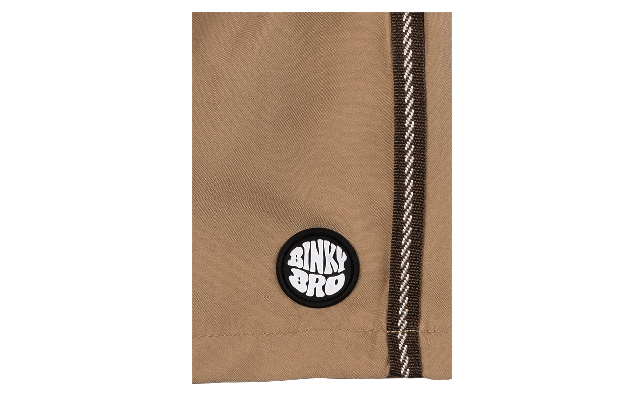 Close-up of Bula Bowls Swimmie featuring a tan fabric and BinkyBro logo patch, designed for stylish kids' swimwear.