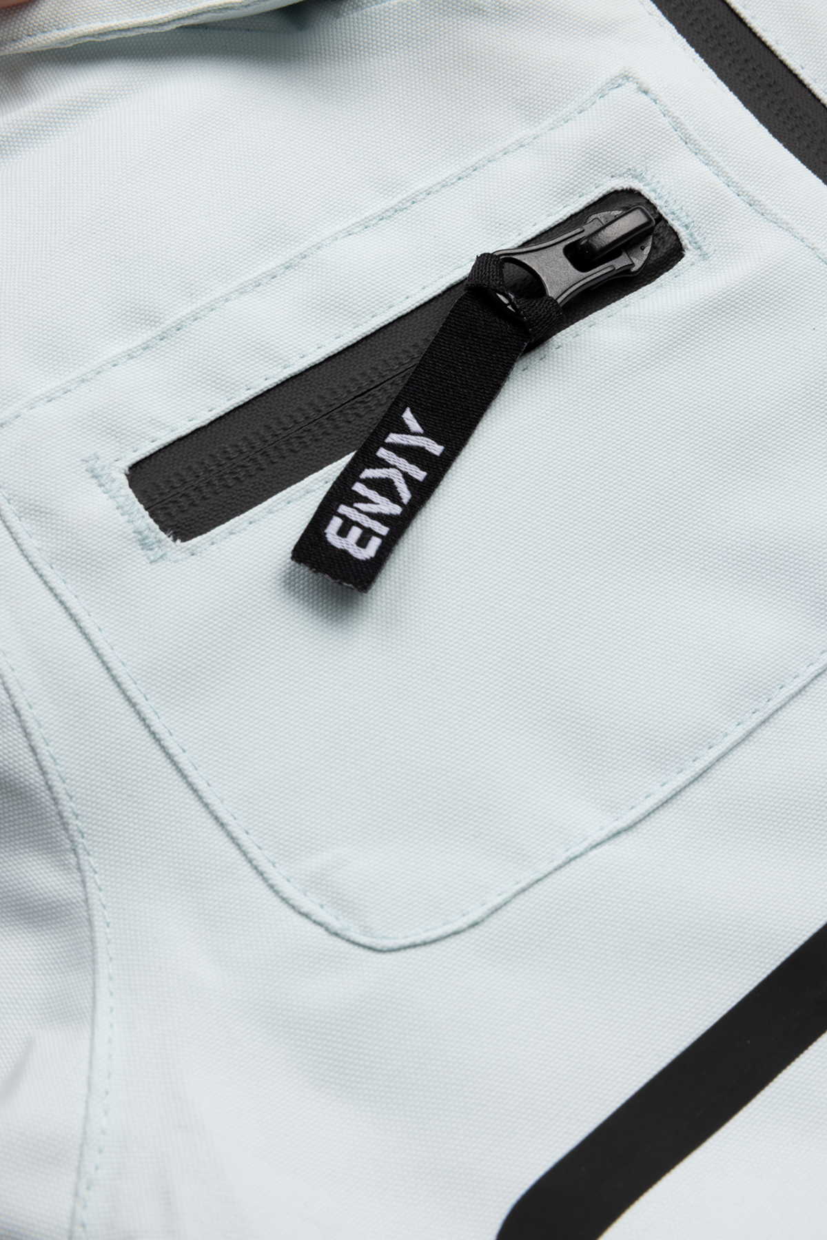 Close-up of a light blue fabric with a zippered pocket, featuring a black pull tab labeled "Roxy." Ideal for outdoor adventures.