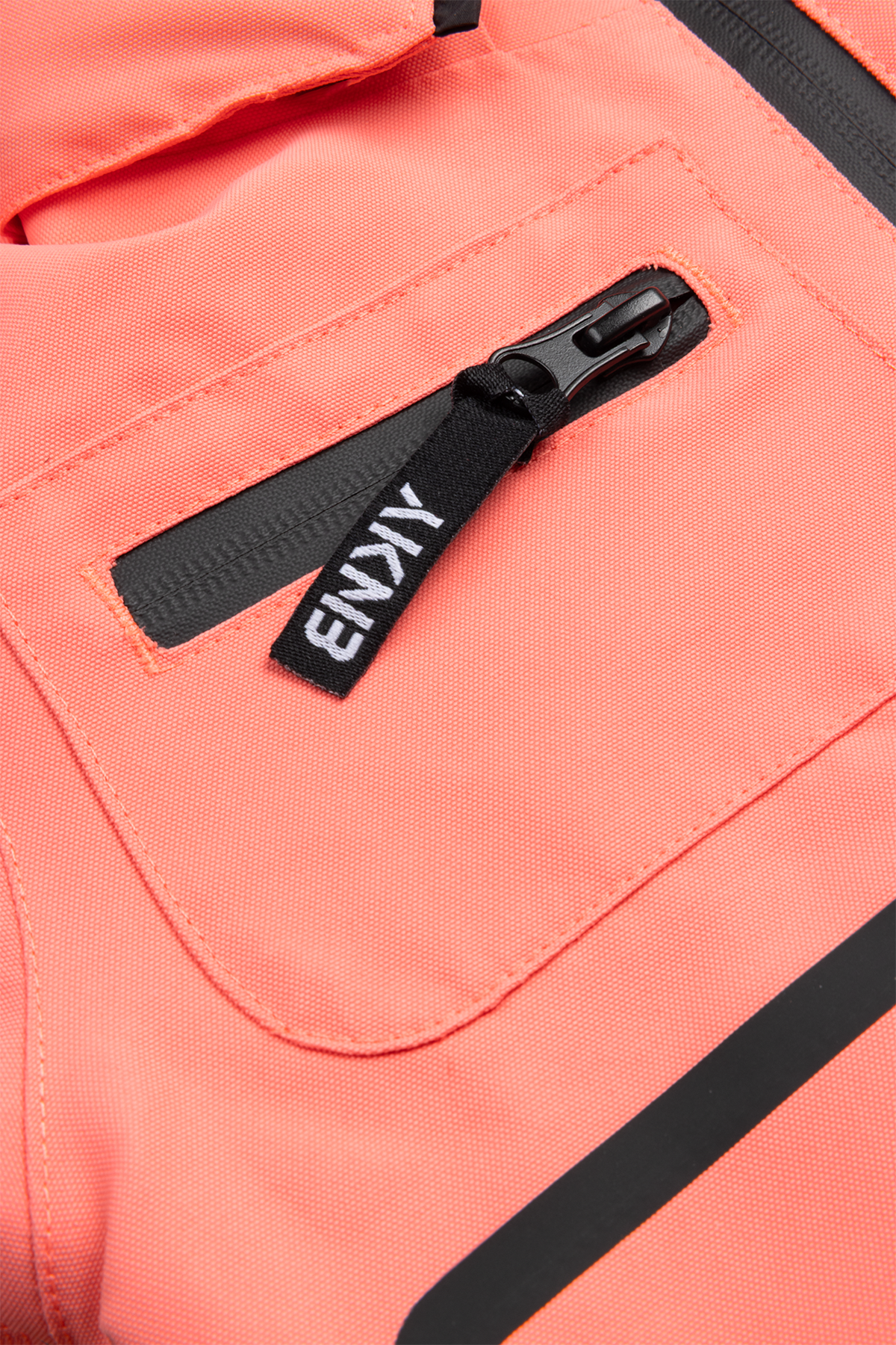 Close-up of the 99-90 Roxy Georgia Peach jacket showing a zippered pocket and brand tag on a vibrant coral fabric.