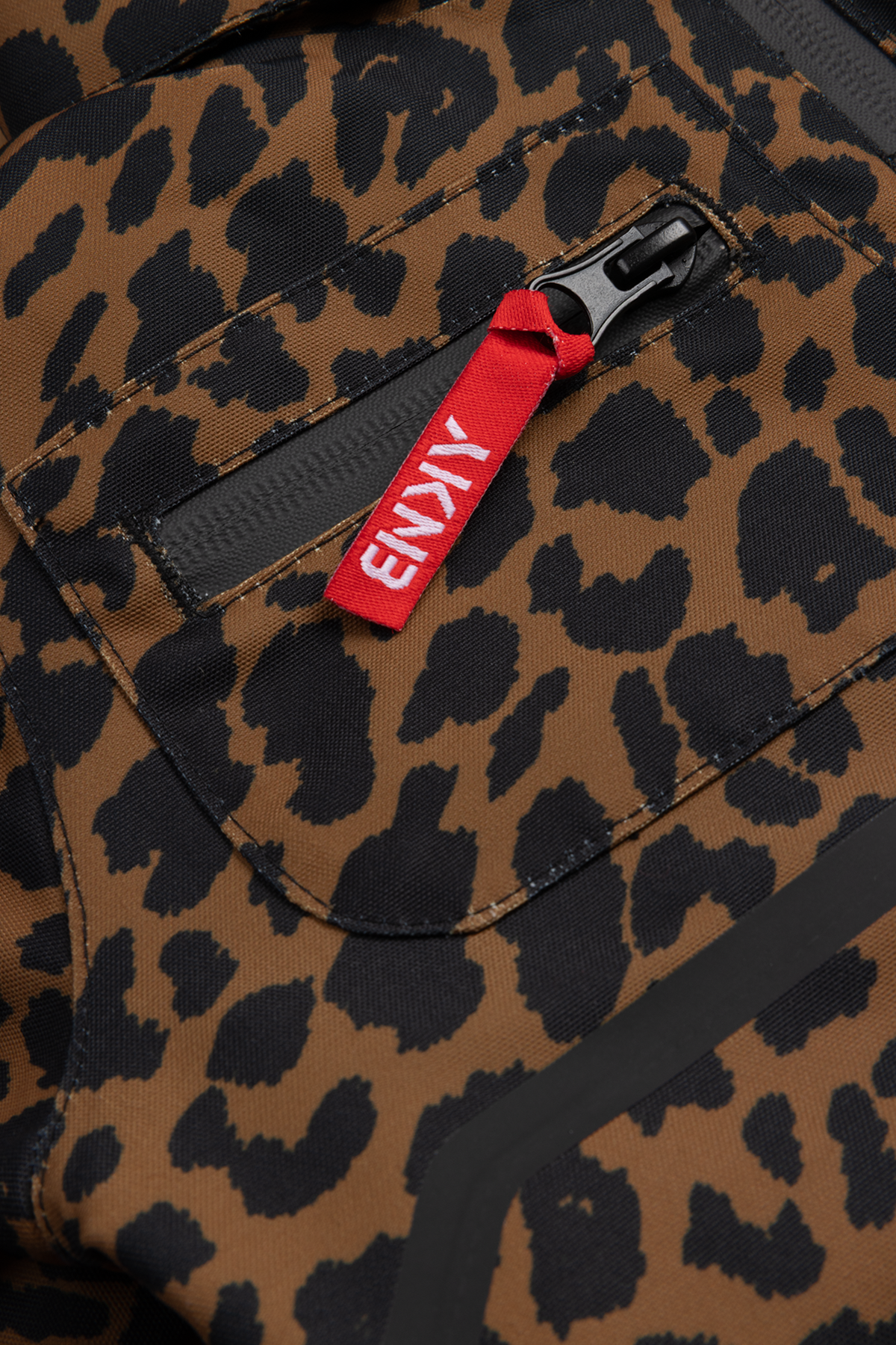 Stylish Roxy Cheetah print fabric featuring a zippered pocket with a red pull tab, perfect for active youth apparel.