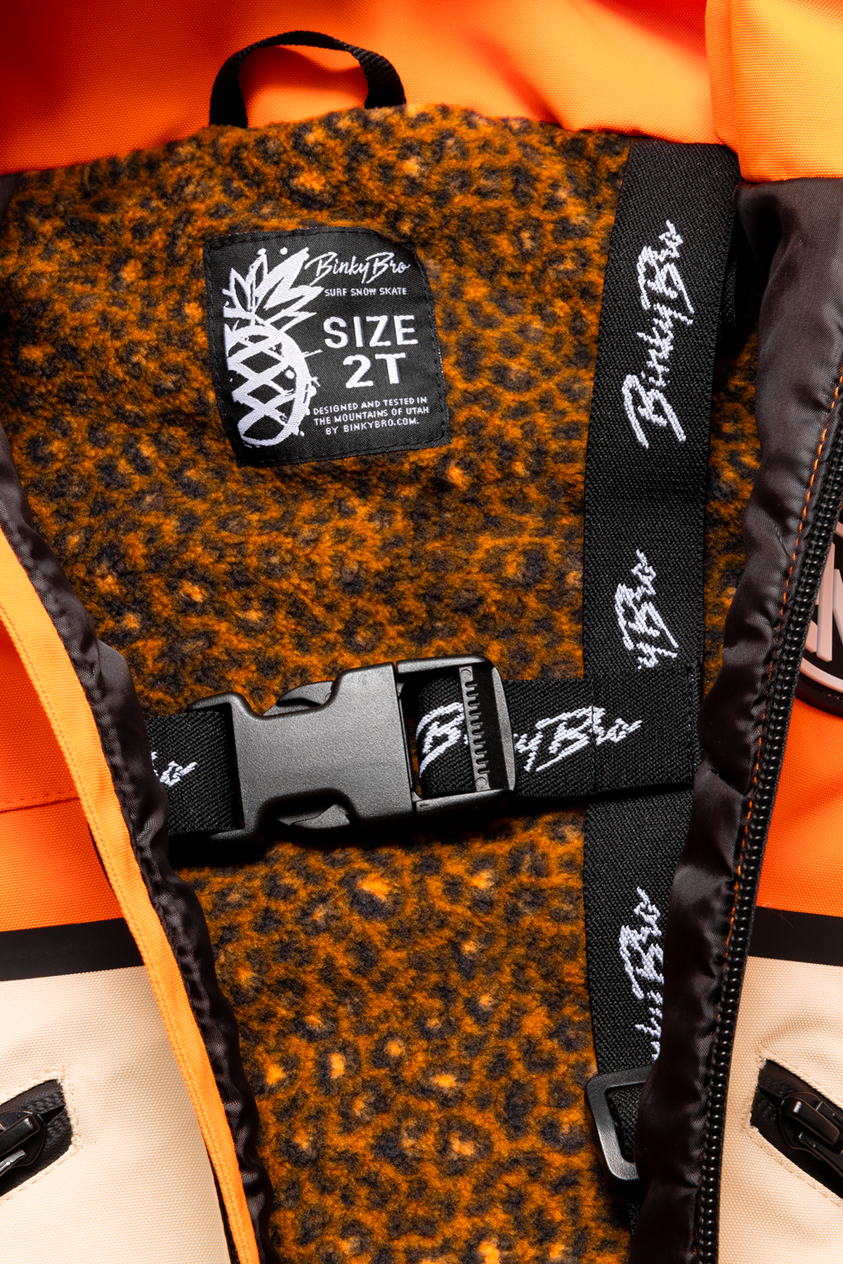 Interior view of the BinkyBro Dragonfire jacket featuring a cozy lining, size tag, and adjustable strap for toddlers.