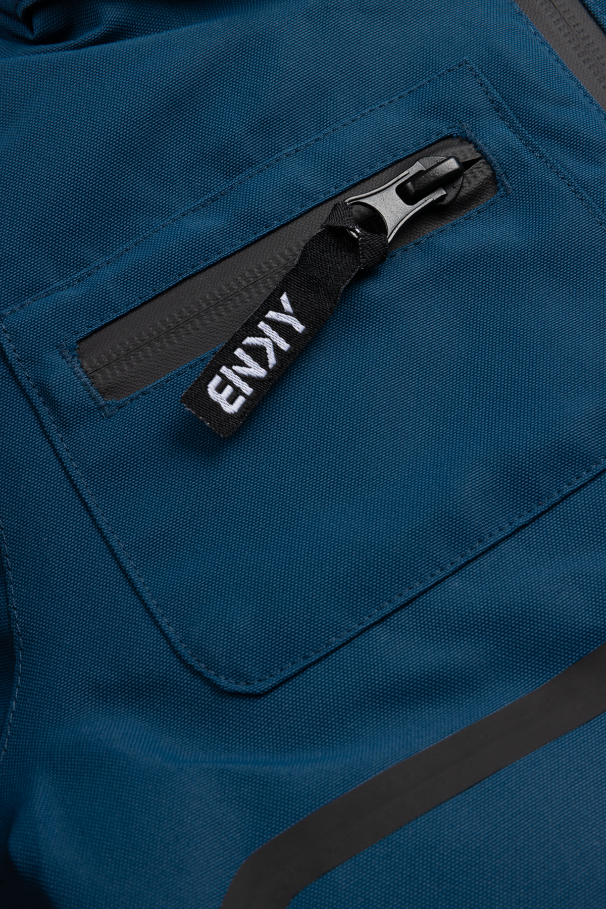 Close-up of the 99-90 BNKY Gibralta jacket featuring a zippered pocket and branded zipper pull in a deep blue fabric.