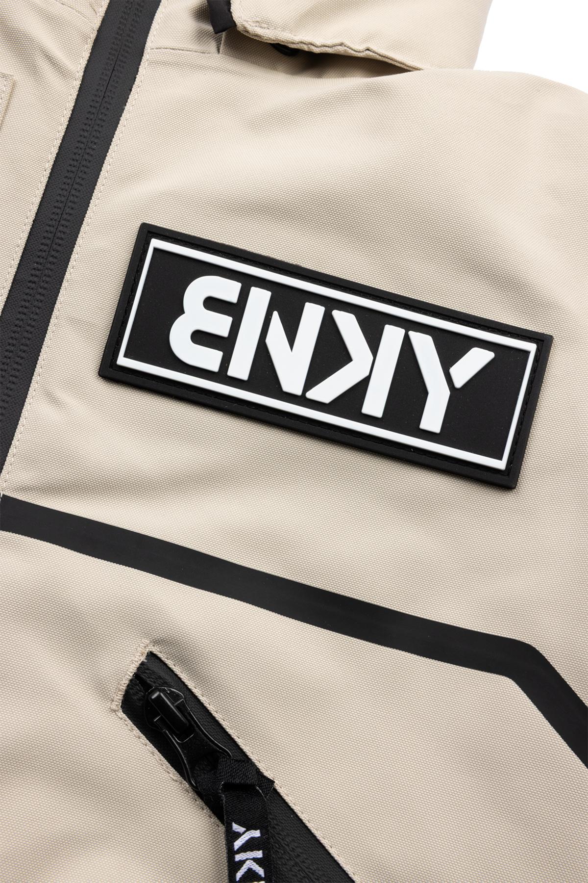 Close-up of the BNKY Island Fossil jacket featuring a bold black logo patch and sleek zipper detail on a beige fabric.