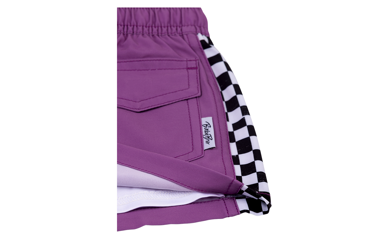 Stylish purple shorts featuring a checkered side panel, perfect for kids embracing a surf-snow-skate lifestyle.
