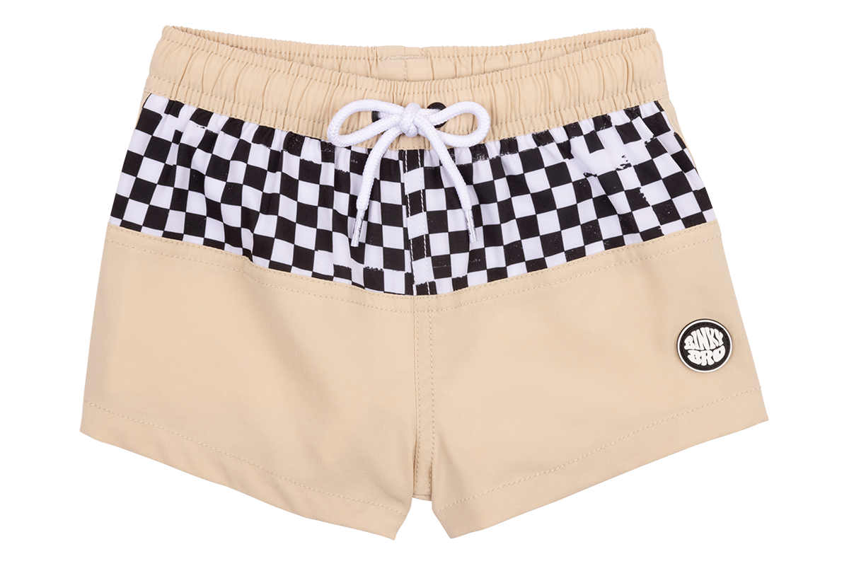 Beige swim shorts with a black and white checkered waistband and a BinkyBro logo patch. Ideal for stylish kids.