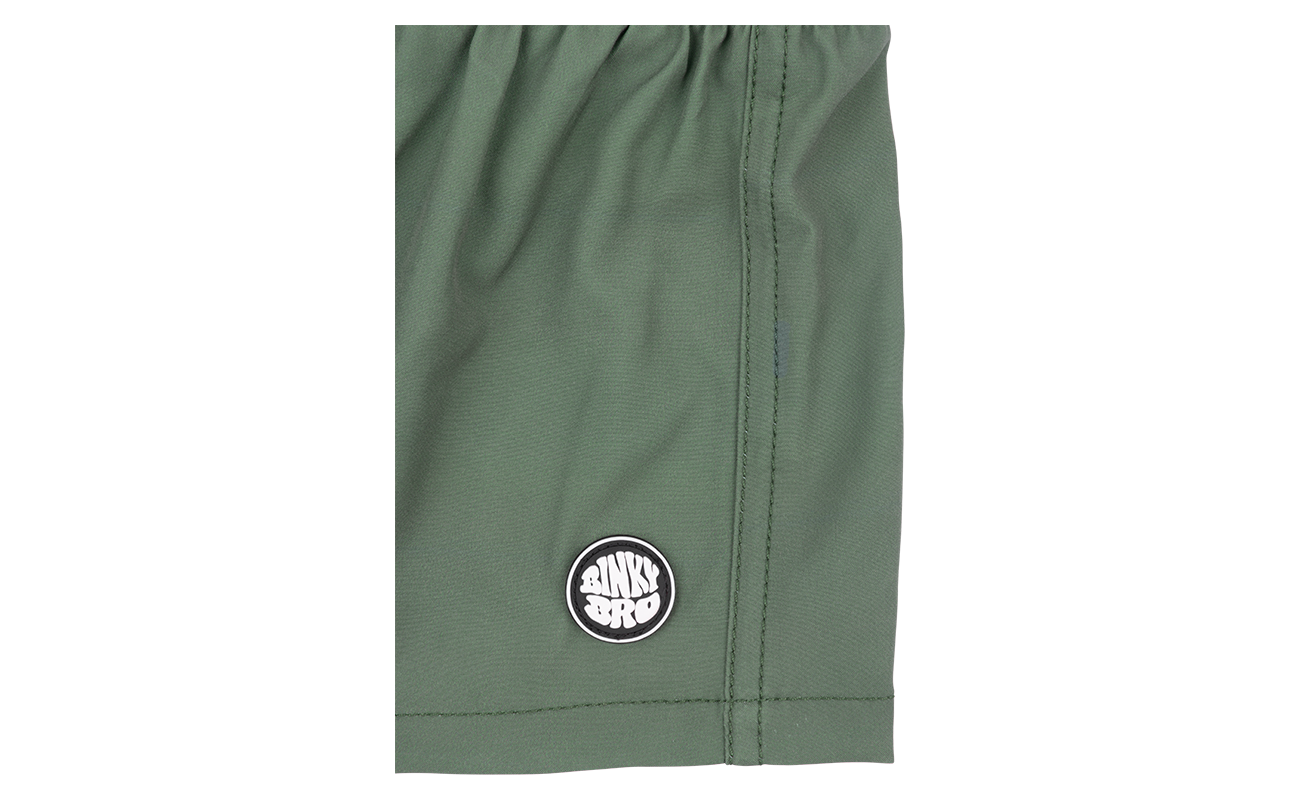 Close-up of the Hubba Hideout shorts in olive green featuring a circular BinkyBro logo on the hem.