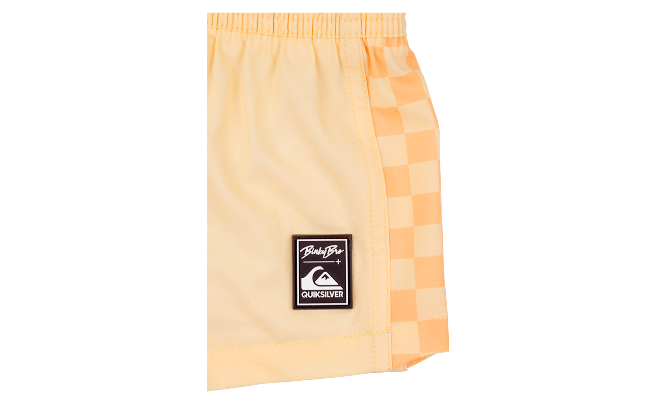 Stylish peach checkered swim shorts featuring a logo patch, perfect for kids embracing a surf-snow-skate lifestyle.