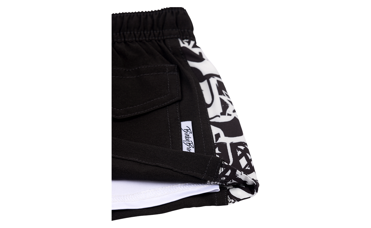 Stylish black shorts featuring a unique patterned side panel, designed for kids with a surf-snow-skate lifestyle.