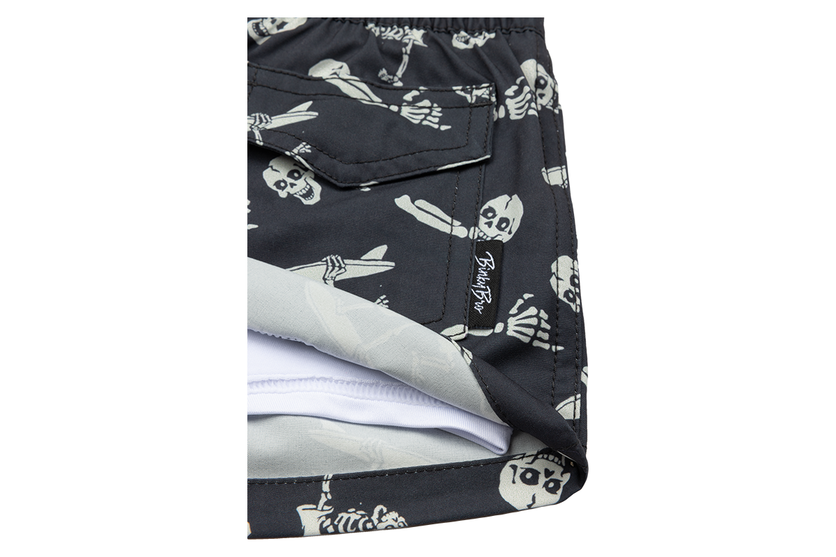 Stylish black swim trunks featuring a playful crossbones and skeleton design, perfect for kids' summer adventures.