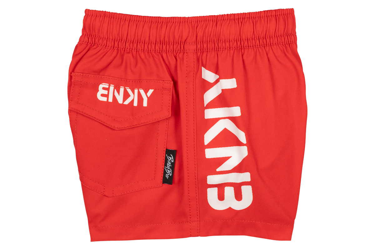 Bright red swim shorts featuring a side pocket and bold white branding, perfect for active kids enjoying summer fun.