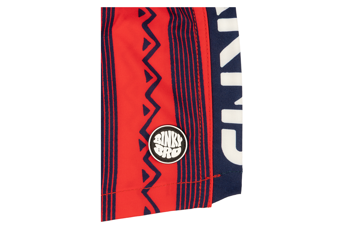 Stamped Crimson swim shorts featuring bold red and navy patterns with a BinkyBro logo patch on the side.