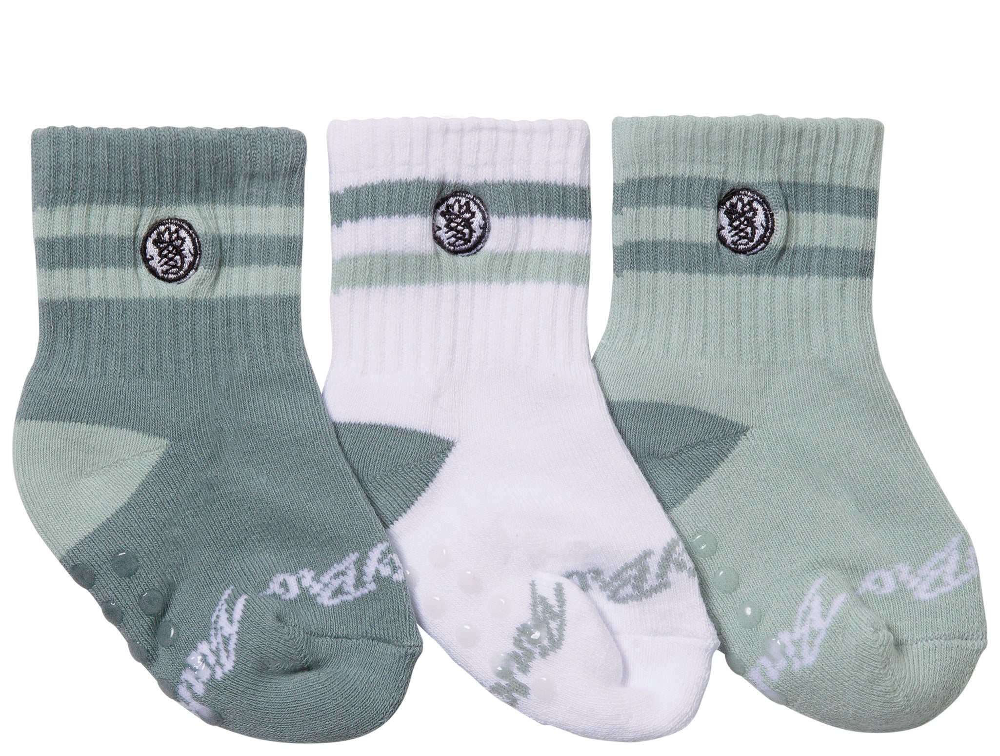 Three pairs of toddler socks in shades of green and white, featuring a pine logo and non-slip grips on the soles.