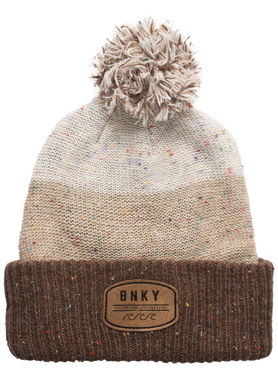 Cozy Sundance Pom beanie in Maca features a speckled cream knit and a brown ribbed cuff with a logo patch. Perfect for kids.