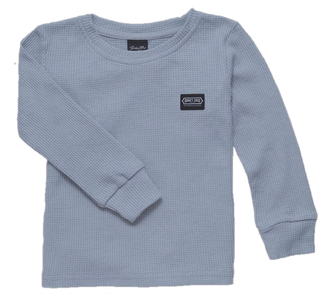 Muted blue long-sleeve thermal shirt for kids featuring a small logo patch on the chest. Ideal for stylish layering.