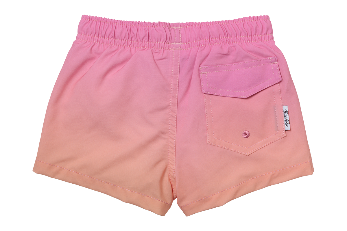 Pink gradient swim shorts with an elastic waistband and a back pocket, designed for infants and toddlers.