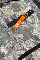 Close-up of the 99-90 BNKY Camo fabric featuring a zippered pocket with an orange tag, showcasing a nature-inspired design.