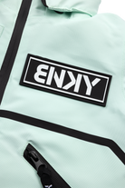 Dusty teal jacket featuring a bold black BNKY logo patch and zippered pockets, perfect for stylish outdoor adventures.