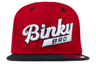 Red snapback hat with a black brim featuring the embroidered "Binky Bro" logo in white, designed for stylish kids.