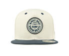 Stylish cream snapback hat with a dark blue brim and a circular logo featuring "Binky Bro Surf Snow Skate.