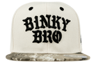 Stylish Durban SB snapback hat featuring a bold black "Binky Bro" logo on a cream base with a patterned brim.