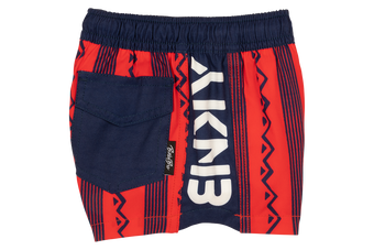 Stylish crimson swim shorts featuring a bold tribal pattern and a navy pocket, perfect for active kids.